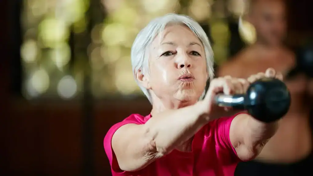 Older woman doing weight training Byfleet to help her strength and longevity 