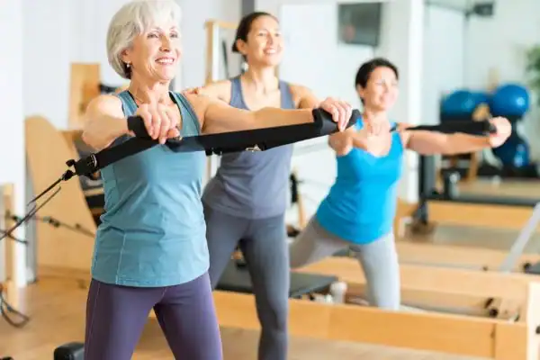 older woman doing weight training Byfleet and resistance in the gym to tone upper arms