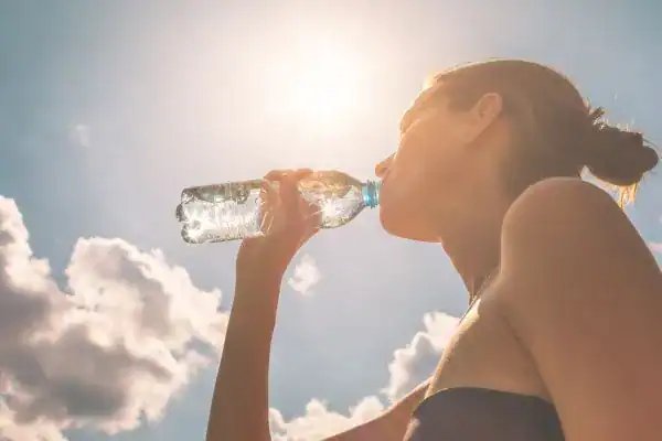 Hydration: The Secret Ingredient for a Toned Stomach and Enhanced Fitness 3 Image of woman drinking water to hydrate Byfleet after run.