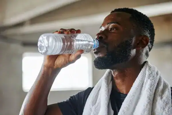 Hydration: The Secret Ingredient for a Toned Stomach and Enhanced Fitness 1 Image of man drinking water to improve hydration Byfleet after work out.